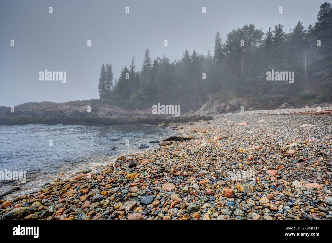 Rochers ronds multicolores sur la plage Little Hunters dans le parc national Acadia, Maine. Marée entrant alors que les vagues s'effondrent. Banque D'Images