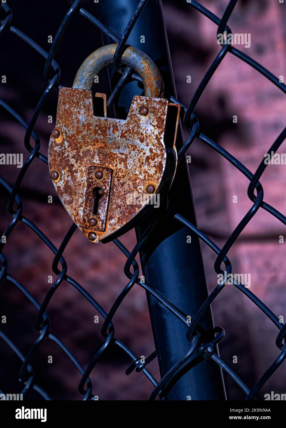 Cadenas rouillé en forme de coeur sur une clôture à chaînette noire . Banque D'Images