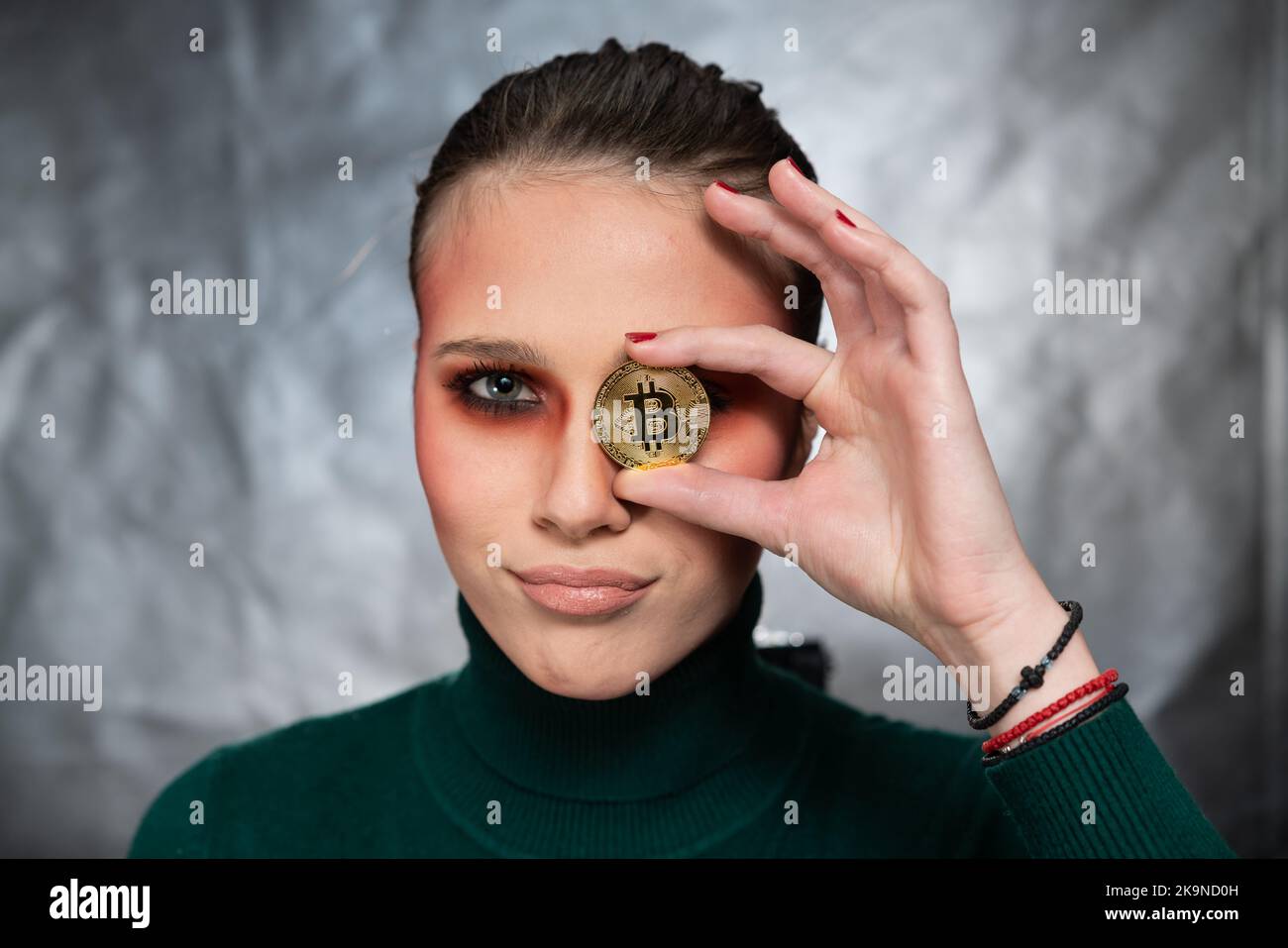 Belle femme tenant un bitcoin, dans différentes expressions du visage, prise de vue en studio Banque D'Images