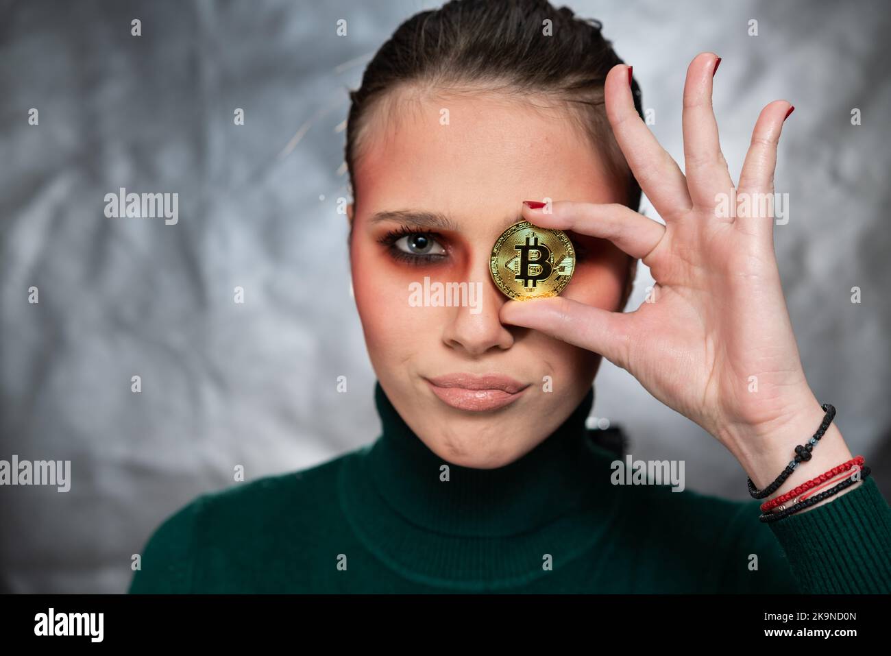 Belle femme tenant un bitcoin, dans différentes expressions du visage, prise de vue en studio Banque D'Images