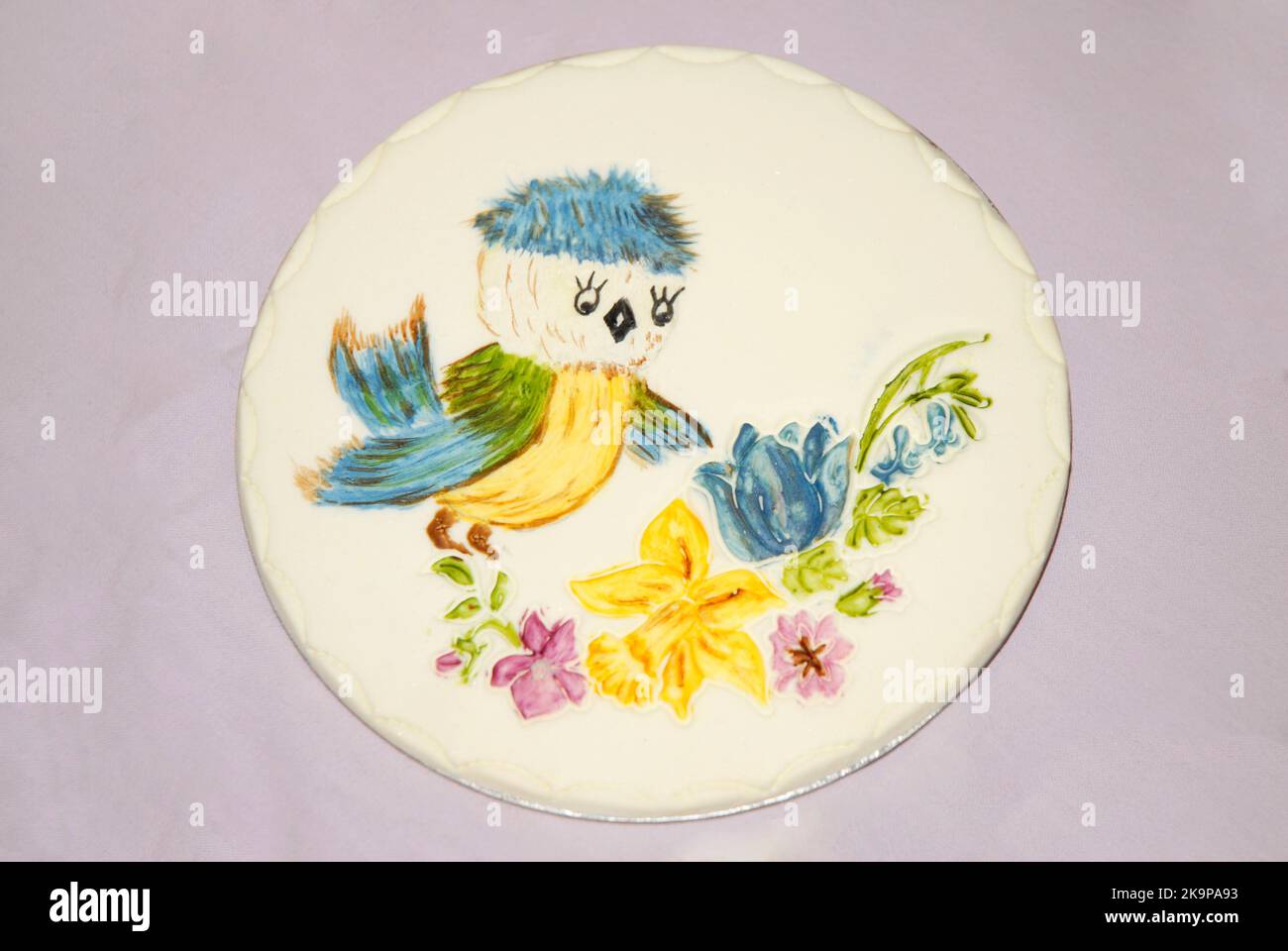 Plaque décorative pour sugarcraft pour gâteaux ou autres occasions festives, montrant un oiseau avec une tête bleue et des ailes regardant des fleurs Banque D'Images