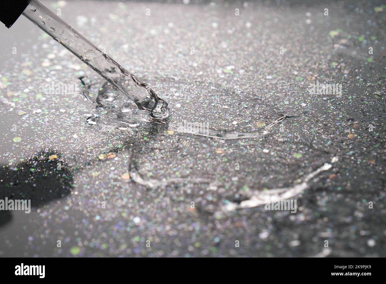 Dégradé. Rétroéclairage. Pipeter avec du sérum ou du gel sur fond noir avec paillettes. Acide hyaluronique hydratant. Gel antibactérien. Cosmétologie. Eau. Banque D'Images