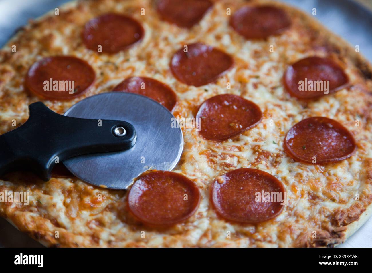 Pizza au pepperoni et au fromage à croûte mince avec coupe-pizza Banque D'Images