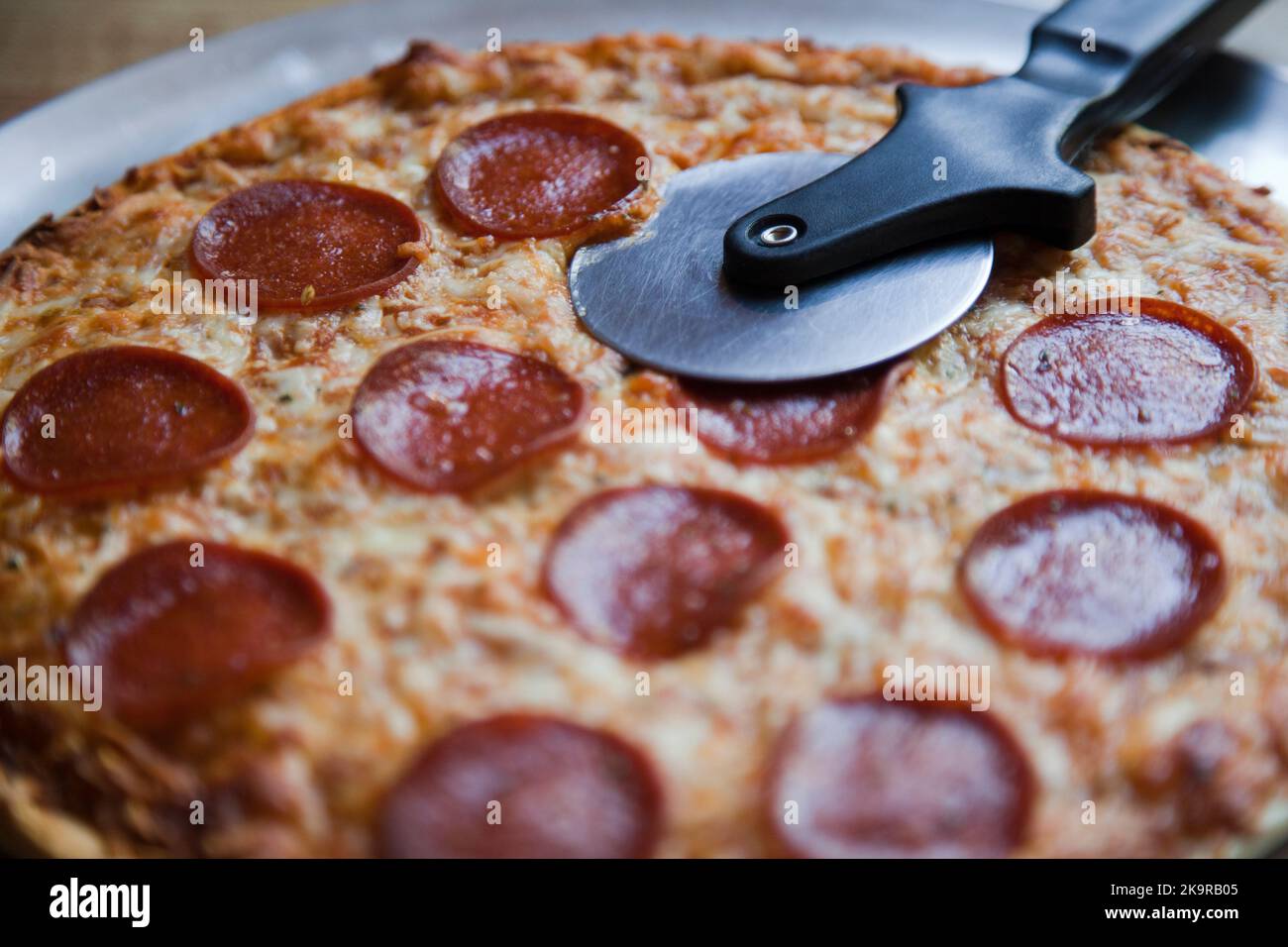 Pizza au pepperoni et au fromage à croûte mince avec coupe-pizza Banque D'Images