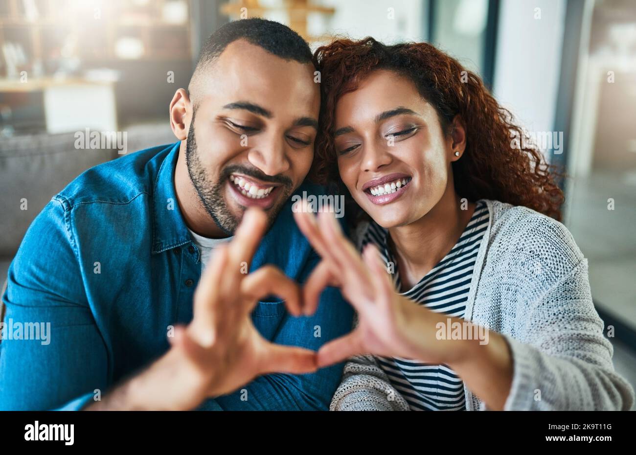 Ensemble est un bel endroit à être. Un jeune couple faisant un geste de coeur avec leurs mains à l'extérieur. Banque D'Images