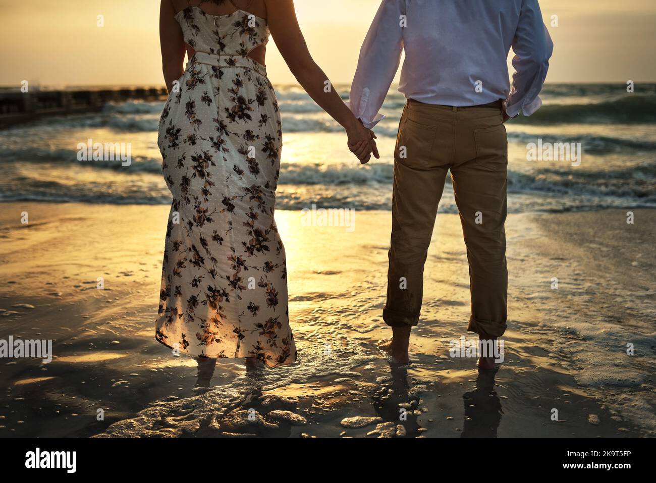 C'est parfait ici au paradis. Vue arrière d'un couple méconnaissable tenant les mains en se tenant sur la plage. Banque D'Images