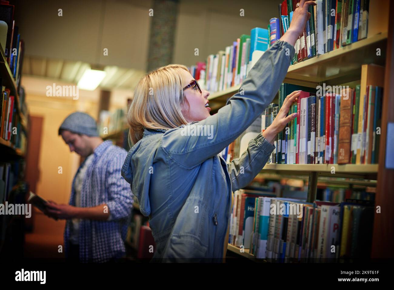Trouver des lectures intéressantes pour compléter ses études. Une étudiante à l'université à la recherche d'un livre dans la bibliothèque du campus. Banque D'Images