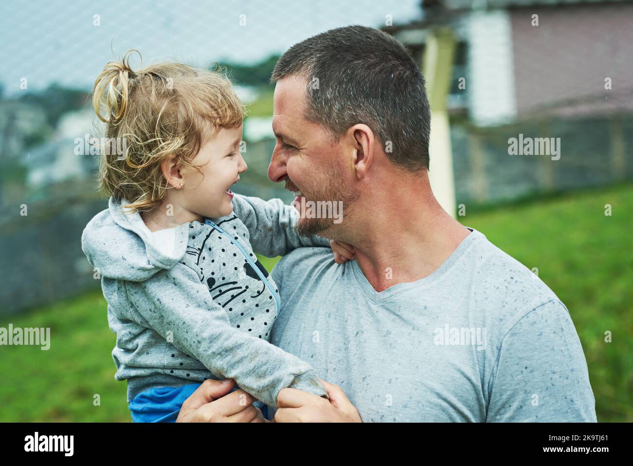 Fille et père amour. Une petite fille joyeuse étant tenue par son père pendant qu'ils regardent les autres yeux dehors pendant un jour pluvieux. Banque D'Images
