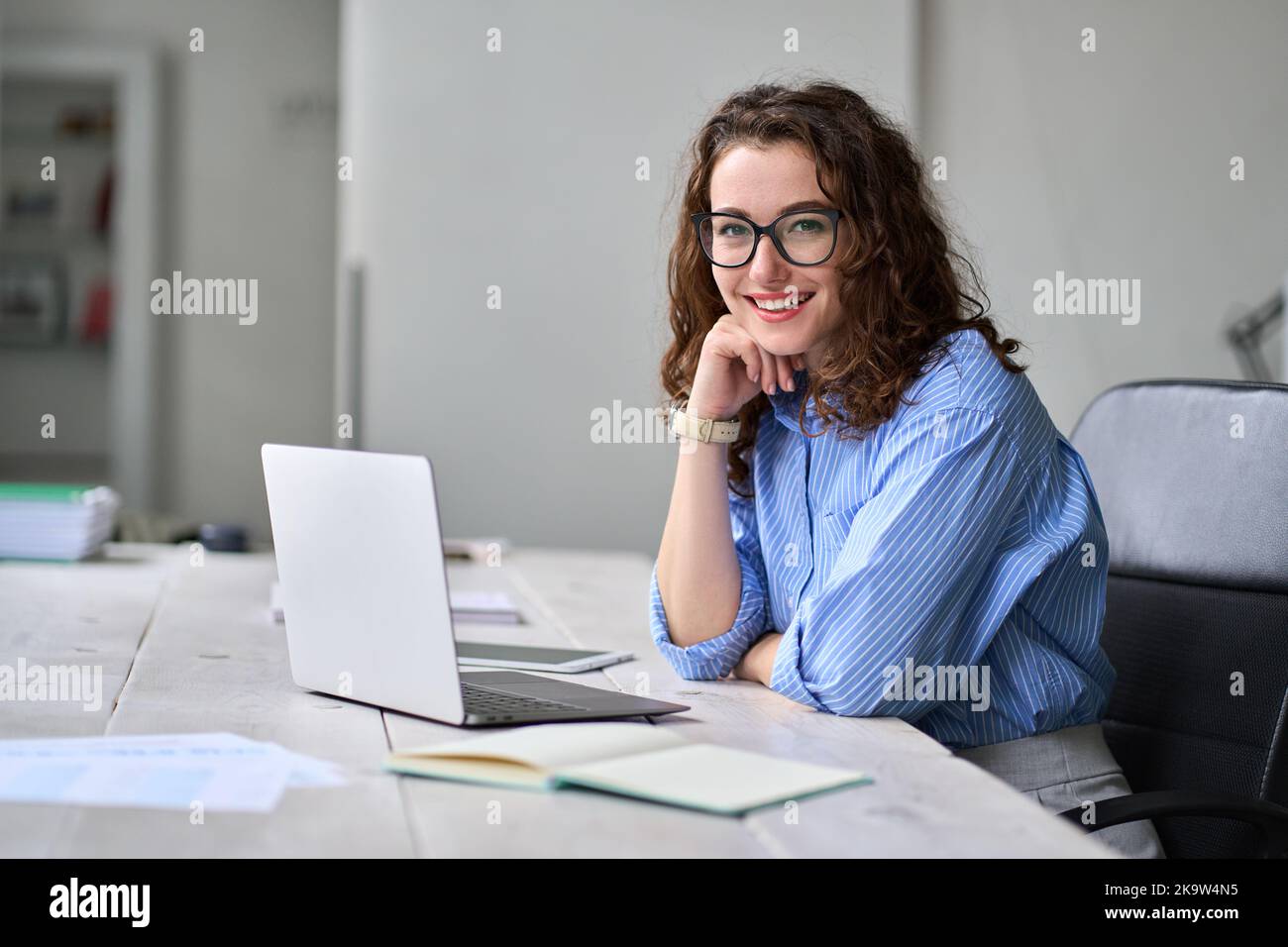 Jeune femme d'affaires heureuse assise à une table de bureau travaillant sur un ordinateur portable. Portrait Banque D'Images