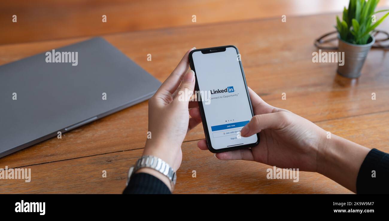 CHIANG MAI, THAÏLANDE - 29 JUIN 2022 : une femme touche un iPhone avec écran LinkedIn. LinkedIn aide à créer un CV et à rechercher un nouvel emploi Banque D'Images