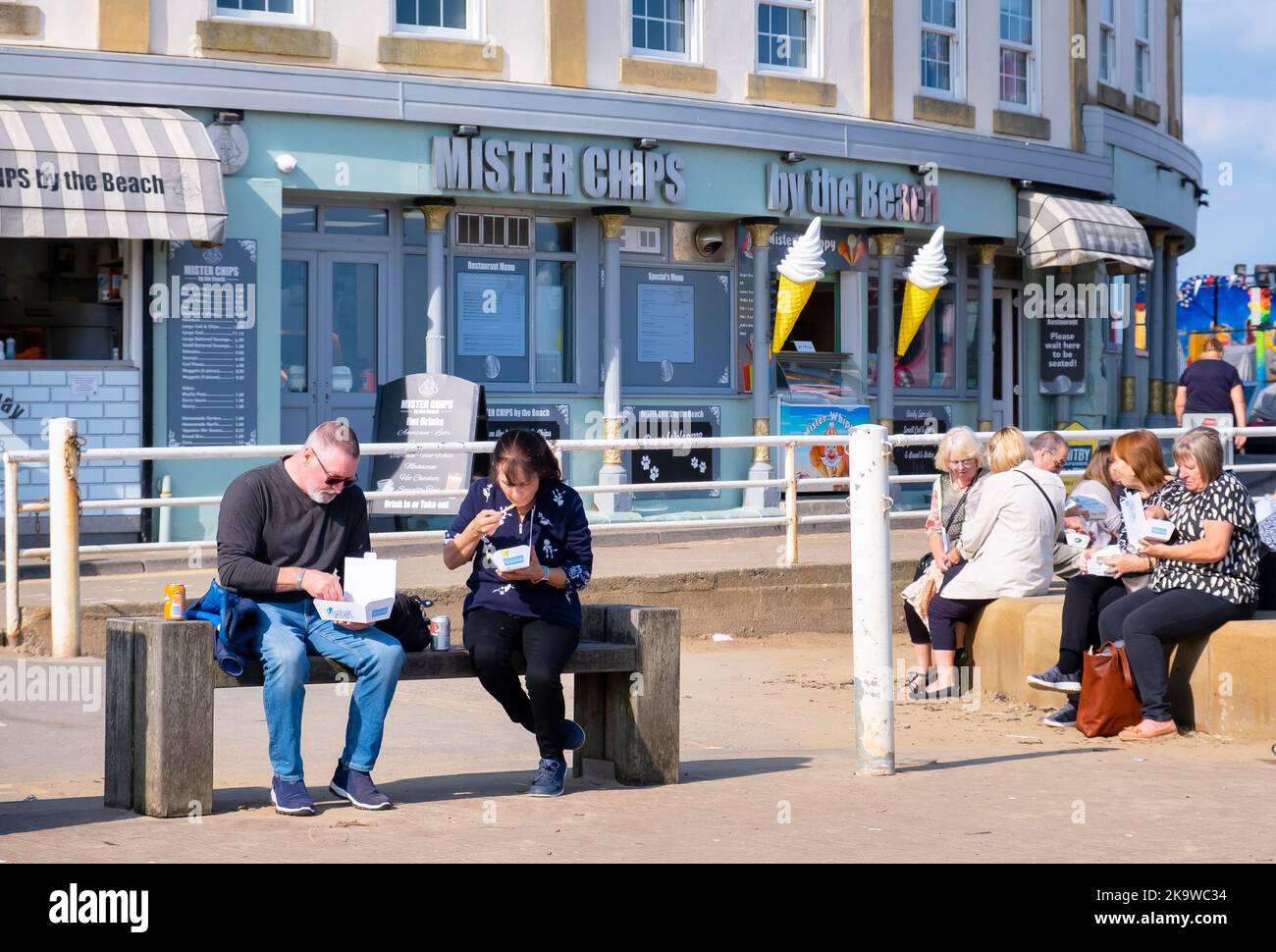 WHITBY, Royaume-Uni - 21 septembre 2022. Les gens assis manger du poisson et des frites sur un banc à l'extérieur d'un magasin de poisson et de puce, Whitby Harbour, North Yorkshire Banque D'Images