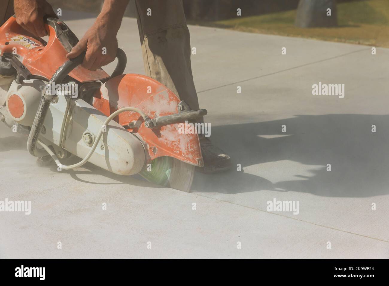 Un employé d'une entreprise de construction coupe des trottoirs en béton avec une scie à disque diamant Banque D'Images