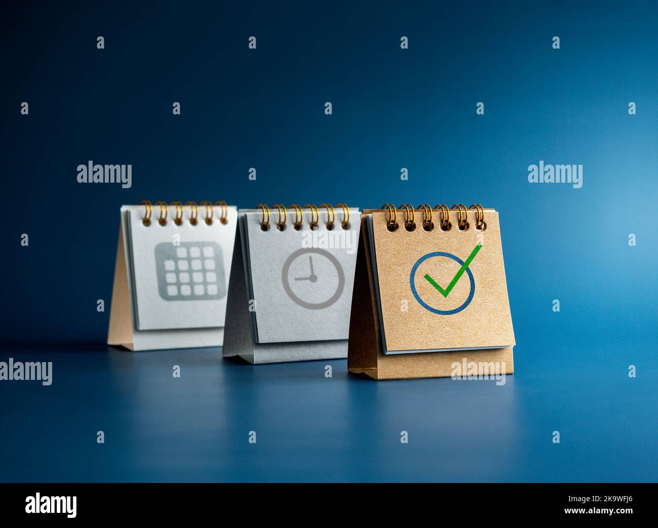 Icône cochée, symbole d'heure et de date sur trois couvertures de calendrier de bureau isolées sur fond bleu, style minimal. Rappel, planification des horaires, âge Banque D'Images