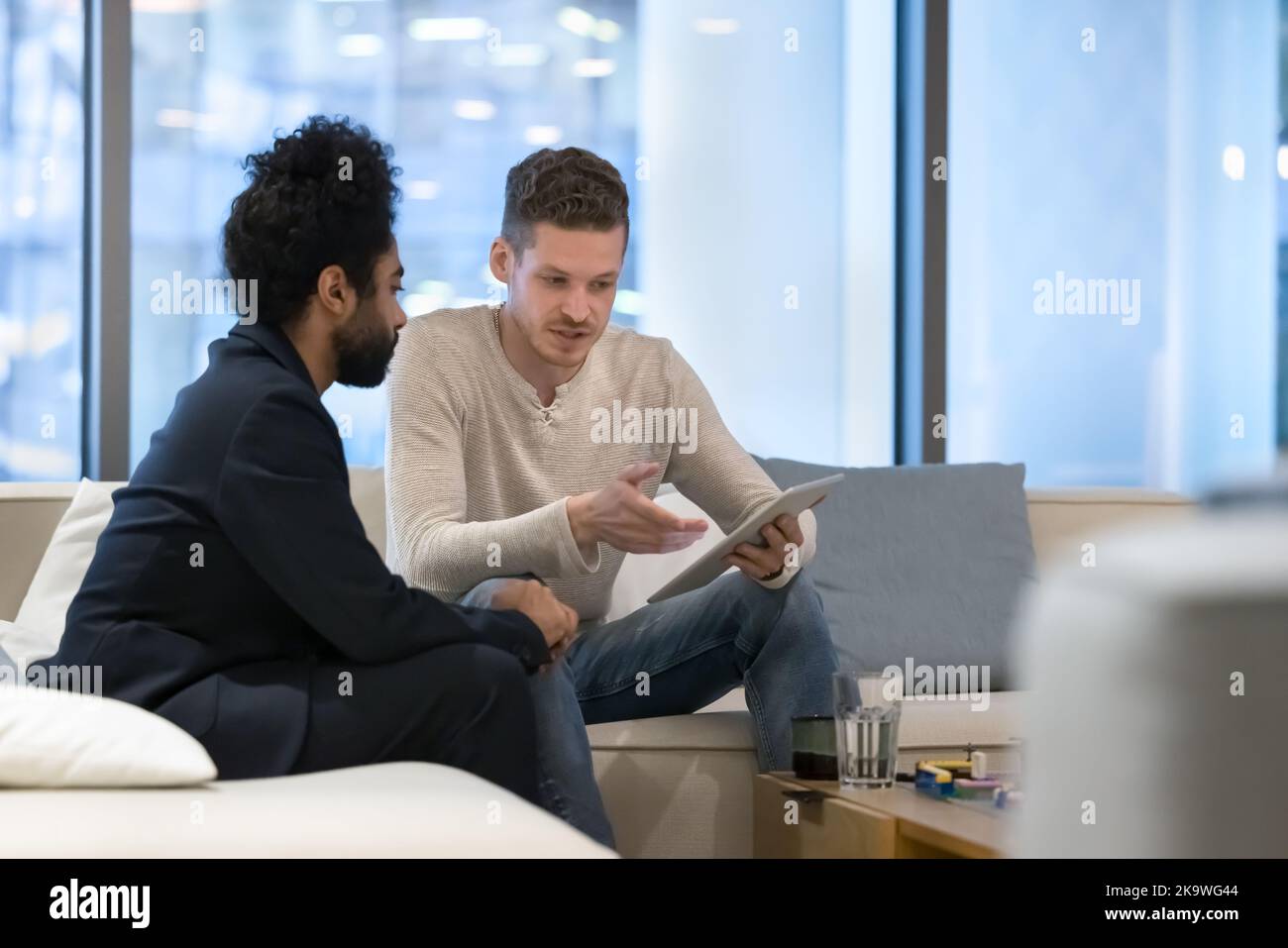 Deux hommes d'affaires multiethniques utilisent une tablette numérique au bureau Banque D'Images
