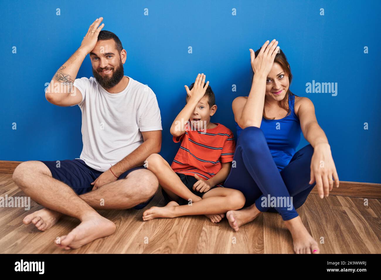 Famille de trois personnes assises sur le sol à la maison surpris par la main sur la tête pour l'erreur, souvenez-vous de l'erreur. oublié, mauvais concept de mémoire. Banque D'Images Famille de trois personnes assises sur le sol à la maison surpris par la main sur la tête pour l'erreur, souvenez-vous de l'erreur. oublié, mauvais concept de mémoire. Banque D'Images