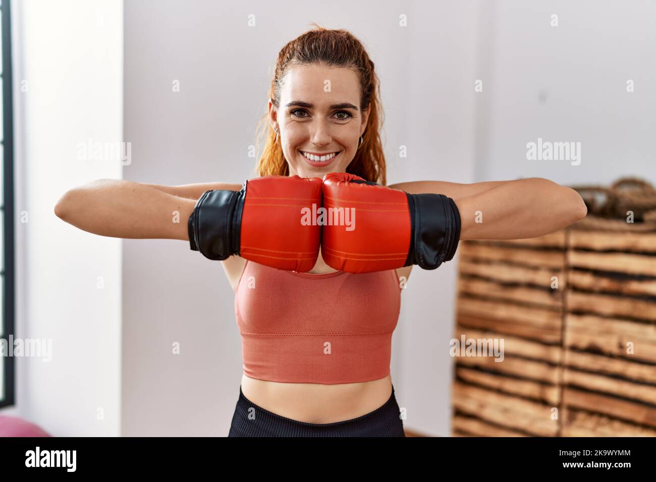 Jeune femme rouge utilisant des gants de boxe souriant avec un sourire heureux et frais sur le visage. Montrant les dents. Banque D'Images