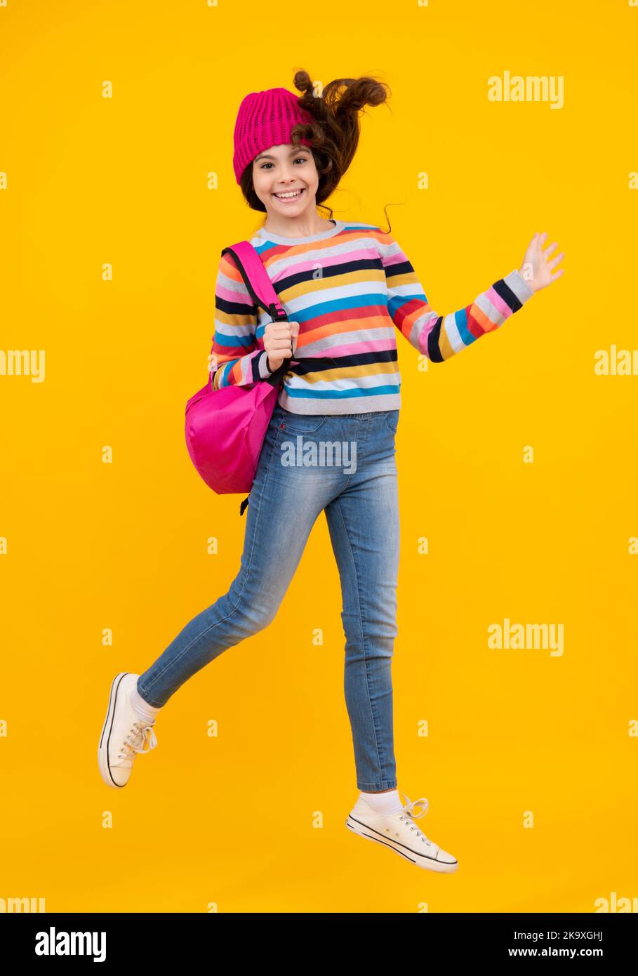 Vacances scolaires d'hiver. Retour à l'école. Adolescente avec chapeau chaud et chandail sur fond jaune isolé studio. École d'hiver. Heureux Banque D'Images