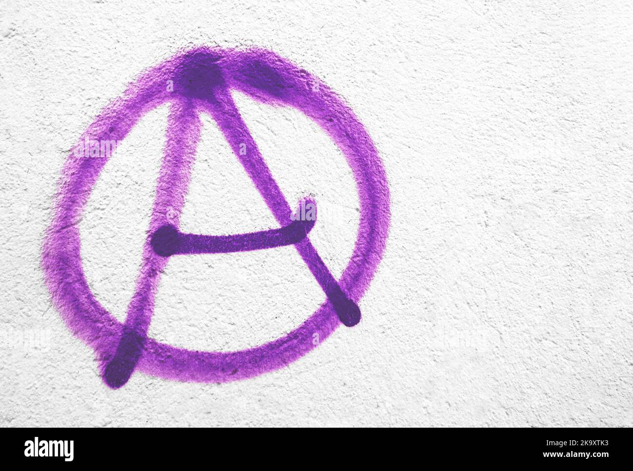 Symbole d'anarchie violet sur le mur. Idéal pour les textures, les arrière-plans et les concepts. Copier l'espace. Banque D'Images