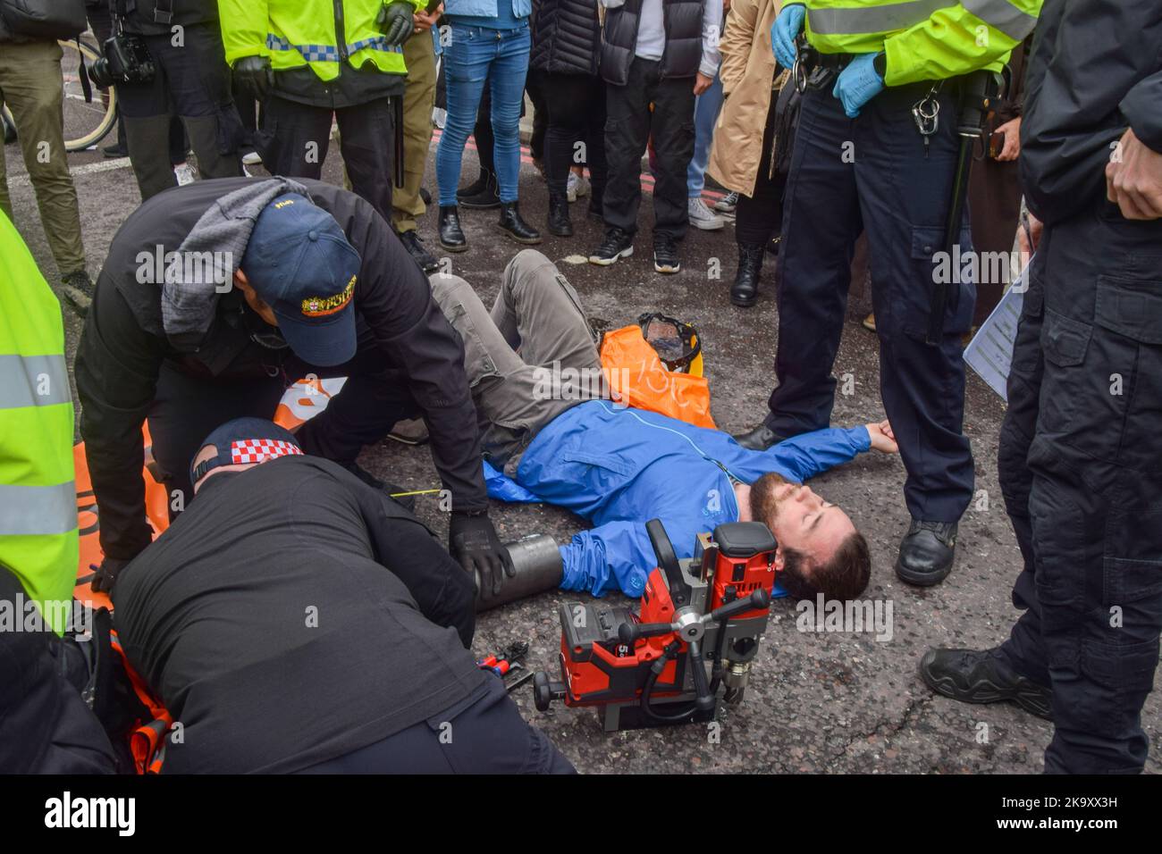 Londres, Royaume-Uni. 30th octobre 2022. Les policiers retirent un tuyau métallique attaché à une paire d'armes des manifestants. Les militants du programme Just Stop Oil ont bloqué les rues à côté du marché de Spitalfields alors qu’ils poursuivaient leurs protestations exigeant que le gouvernement cesse d’émettre de nouvelles licences de combustibles fossiles. Credit: Vuk Valcic/Alamy Live News Banque D'Images