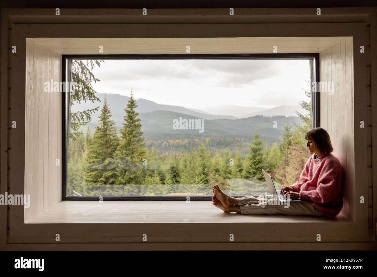 Femme travaille sur ordinateur portable à la maison dans les montagnes Banque D'Images