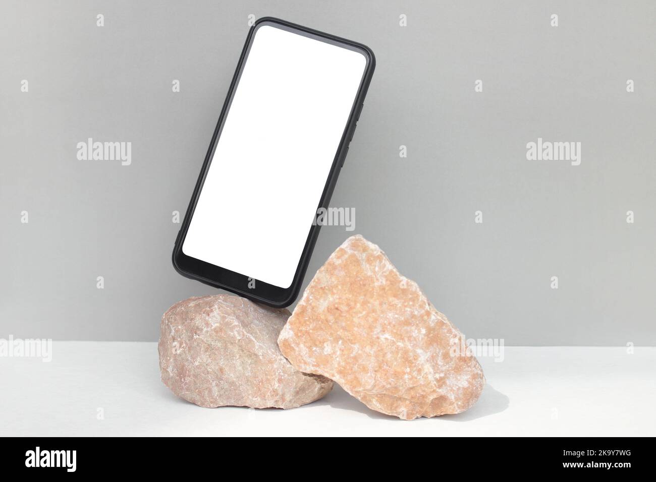 Modèle de smartphone Mockup sur des pierres rouges naturelles sur fond gris.style minimaliste. Banque D'Images
