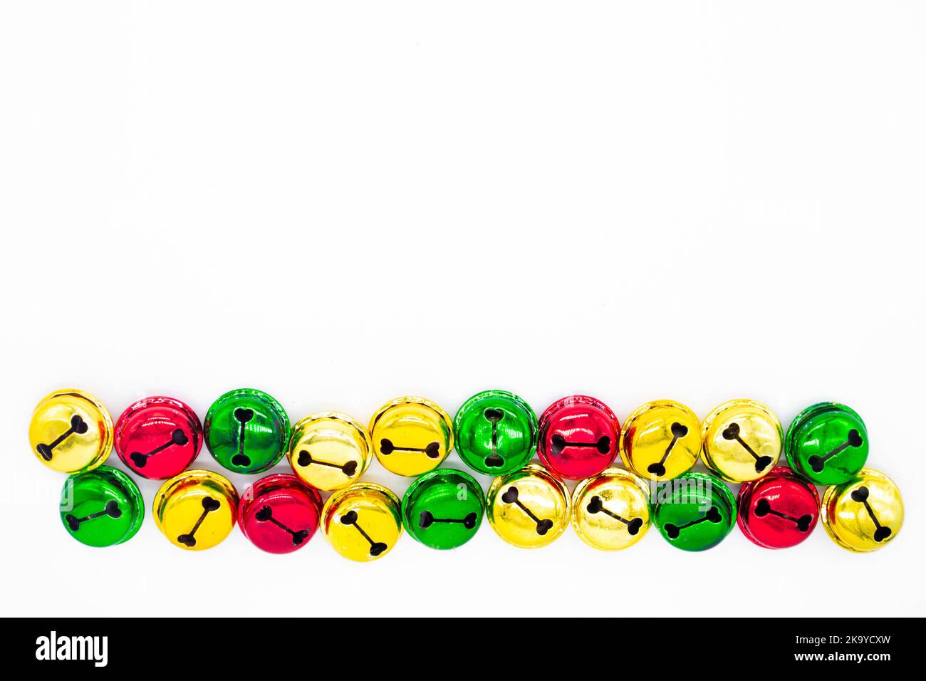 Des cloches de Noël colorées en or, rouge et vert se trouvent sur une rangée. Le concept de Noël. Arrière-plan de vacances. Copier l'espace. Banque D'Images