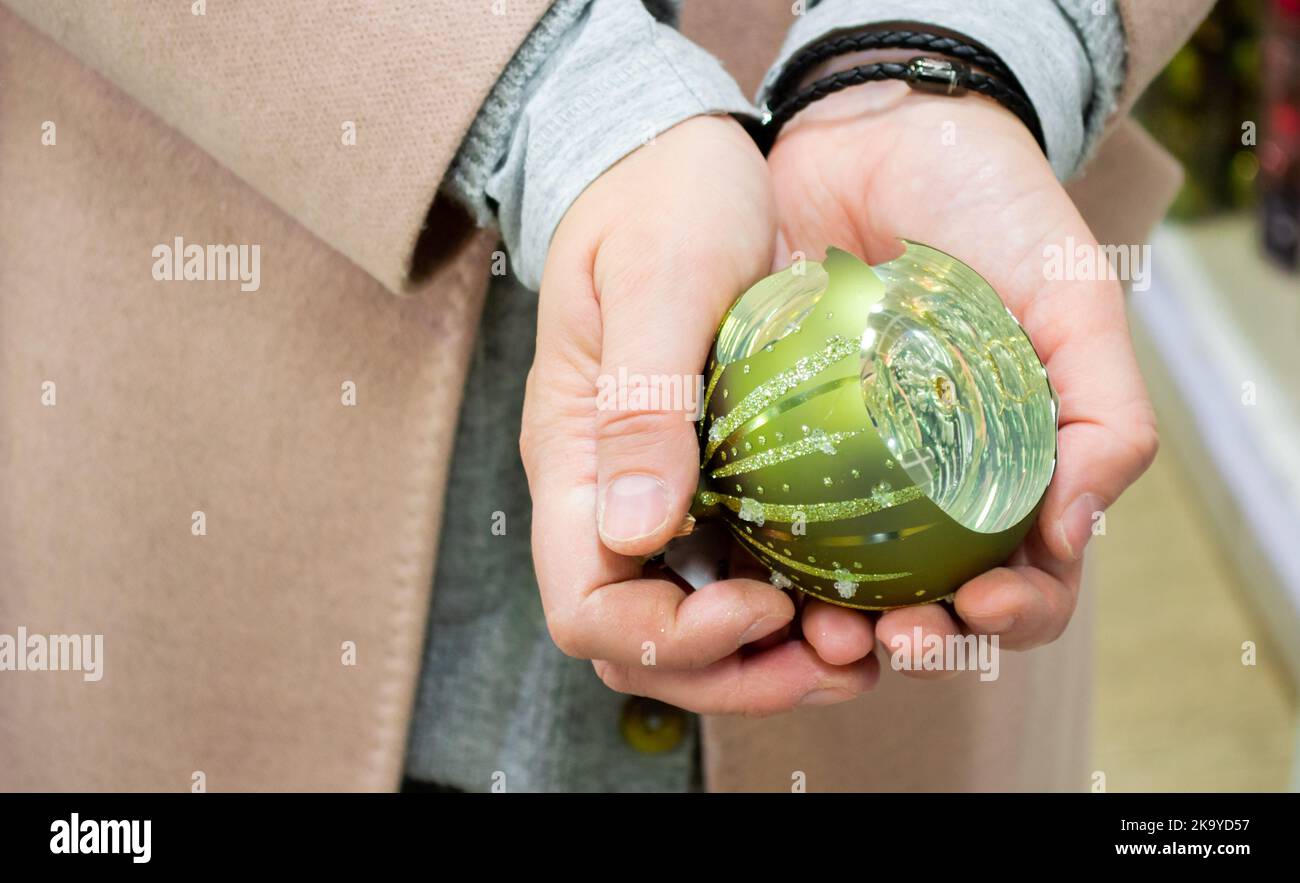 Gros plan d'un sapin de Noël vert en verre cassé dans les mains de la femme. Banque D'Images