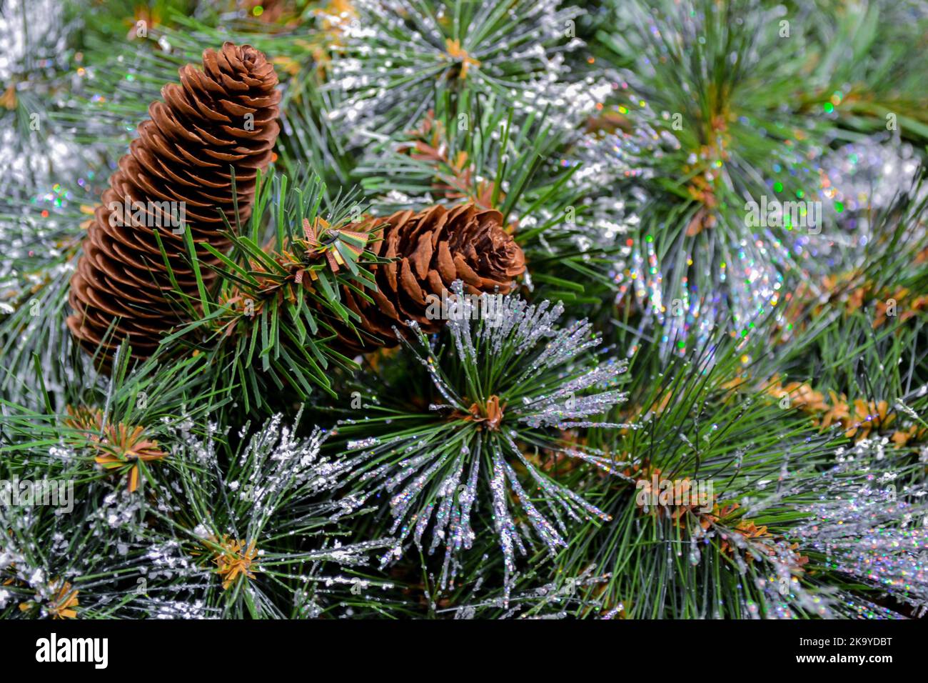 Gros plan d'un arbre de Noël artificiel avec gel pailleté, neige et cônes comme fond de Noël. Copier l'espace Banque D'Images