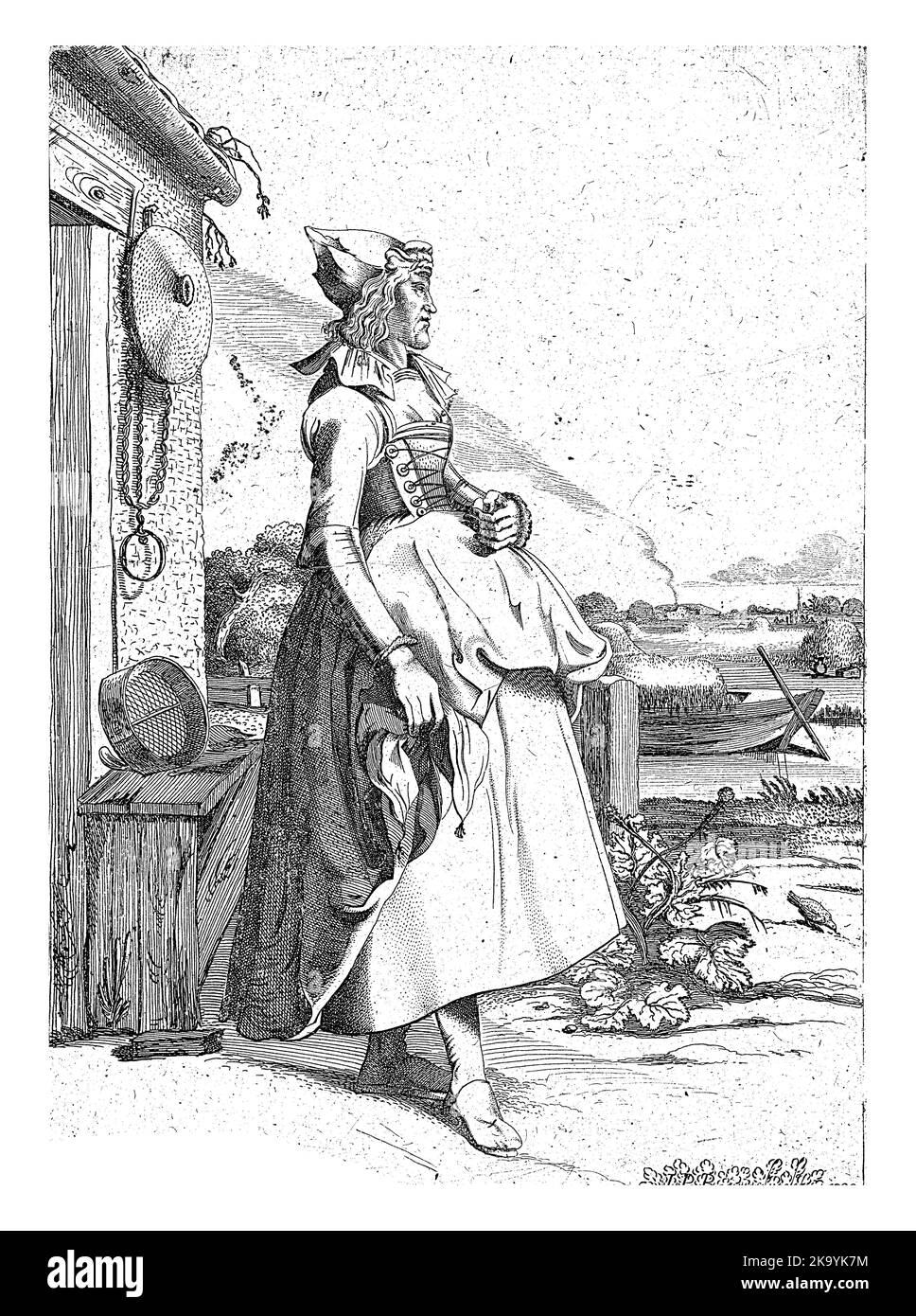 Une jeune femme de Hoorn, vêtue de costume traditionnel, se trouve à côté d'une maison sur le front de mer. Il y a un bateau avec du foin dans le canal. Banque D'Images