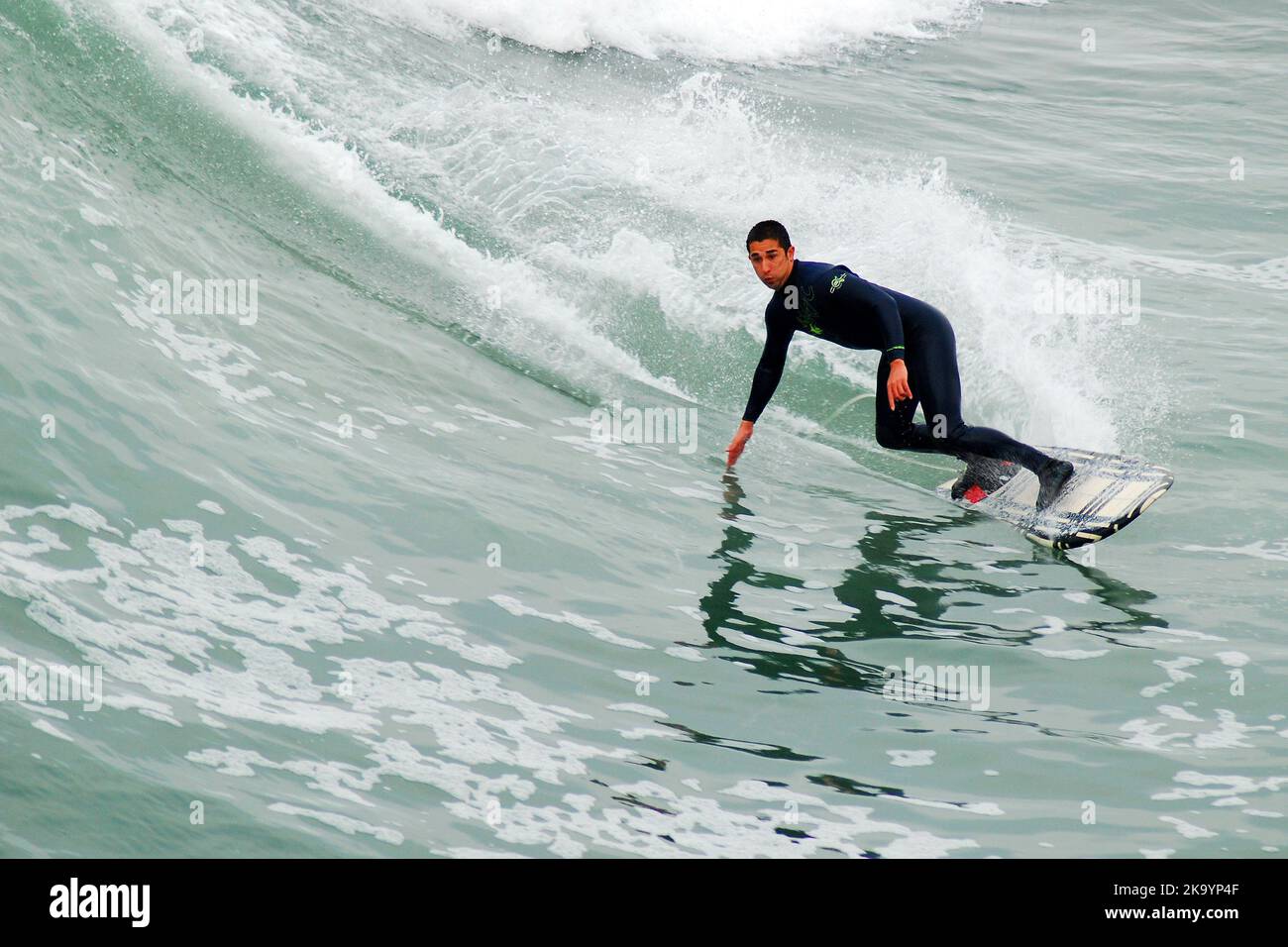 Un surfeur se penche dans une vague alors que sa planche de surf se déforme dans l'eau au large de la côte sud de la Californie Banque D'Images