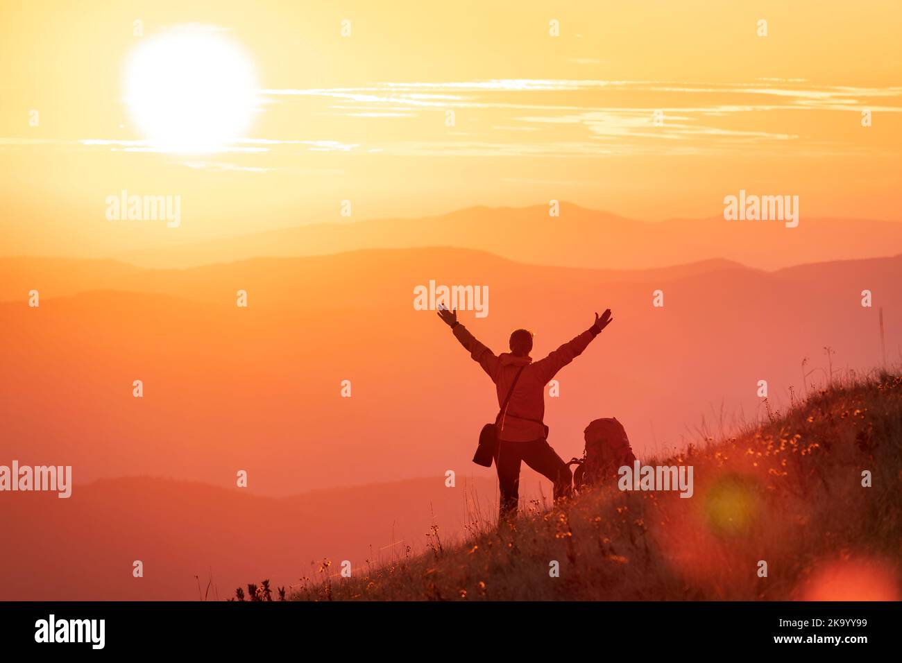 La jeune fille de randonneur rencontre le soleil avec les bras étirés haut dans les montagnes. Symbole du succès, de la réalisation ou de l'illumination Banque D'Images