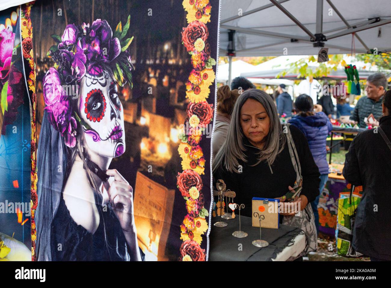 New York, NY, États-Unis. 30th octobre 2022. Mano a Mano: Culture mexicaine sans frontières (Cultura Mexicana Sin Fronteras) a organisé une célébration Dia de Muertos à l'église Saint-Marc In-the-Bowery, avec un autel commémoratif d'offrandes, de photographies et de souvenirs écrits, ainsi que de la nourriture, de l'artisanat et des divertissements mexicains. Une femme dans une cabine d'artisanat est encadrée par un Calavera Catrina suspendu. Credit: Ed Lefkowicz/Alay Live News Banque D'Images