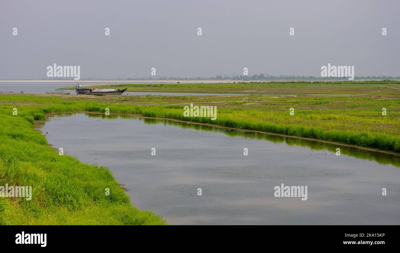 Vue panoramique sur les marais le long de la rive de la rivière Brahmaputra avec bateau en bois près de Dibrugarh, Assam, Inde Banque D'Images
