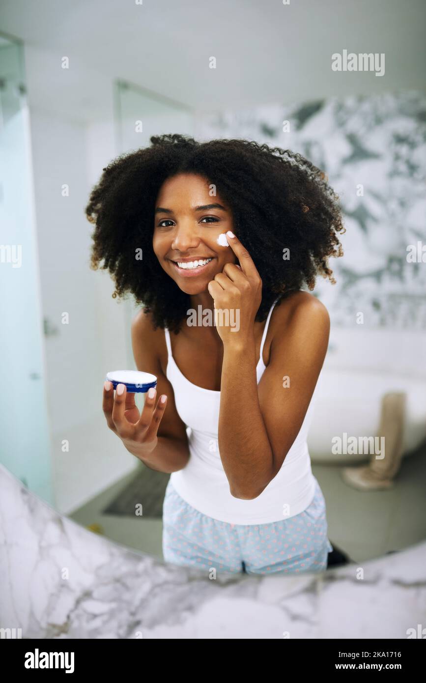 Je ne donne que la meilleure peau. Portrait d'une jeune femme attrayante appliquant un hydratant sur son visage à la maison. Banque D'Images