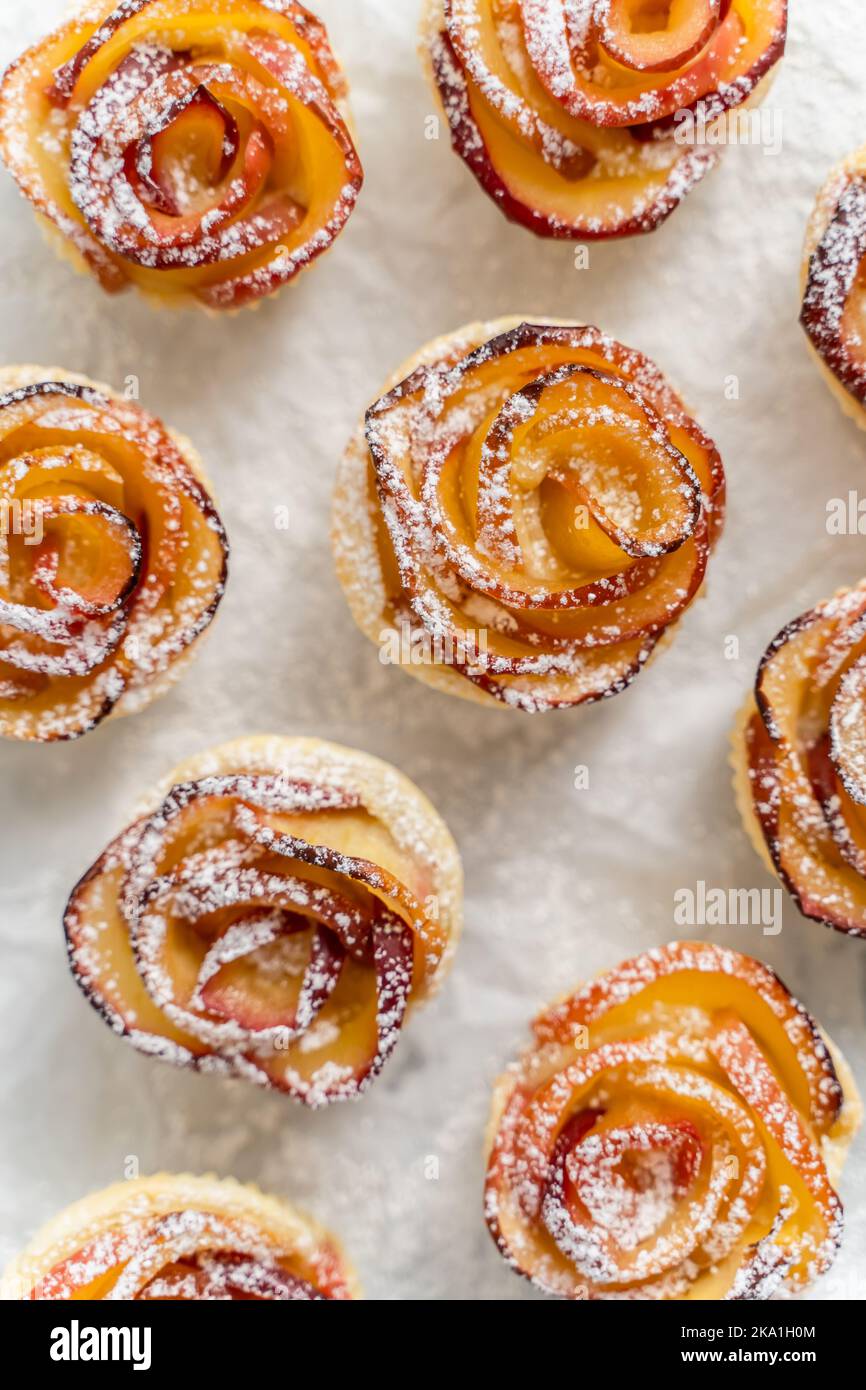 Tartes aux pommes cuites sous forme de roses avec cannelle et clous de girofle sur une plaque à pâtisserie Banque D'Images