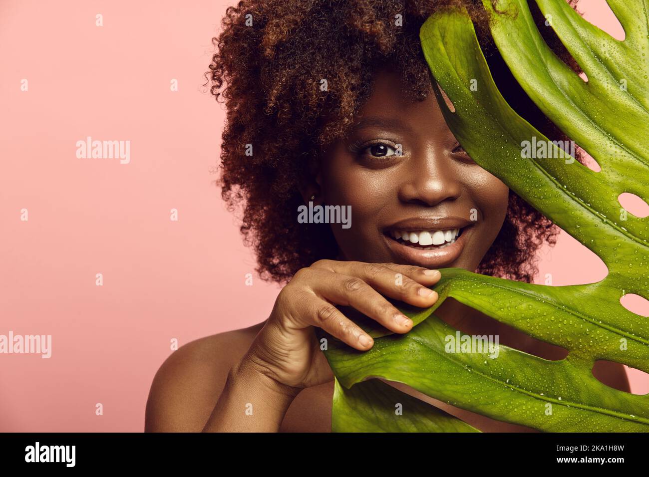 Une fille afro-américaine sort de la feuille de Monstera. Banque D'Images