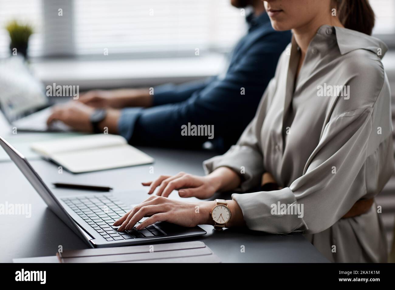 Jeune femme d'affaires ou étudiante en soie grise tapant sur le clavier d'ordinateur portable tout en recherchant des données en ligne ou en effectuant des tâches Banque D'Images