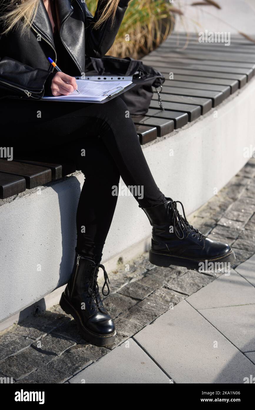 une femme remplit un questionnaire tout en étant assise sur un banc dans la rue Banque D'Images