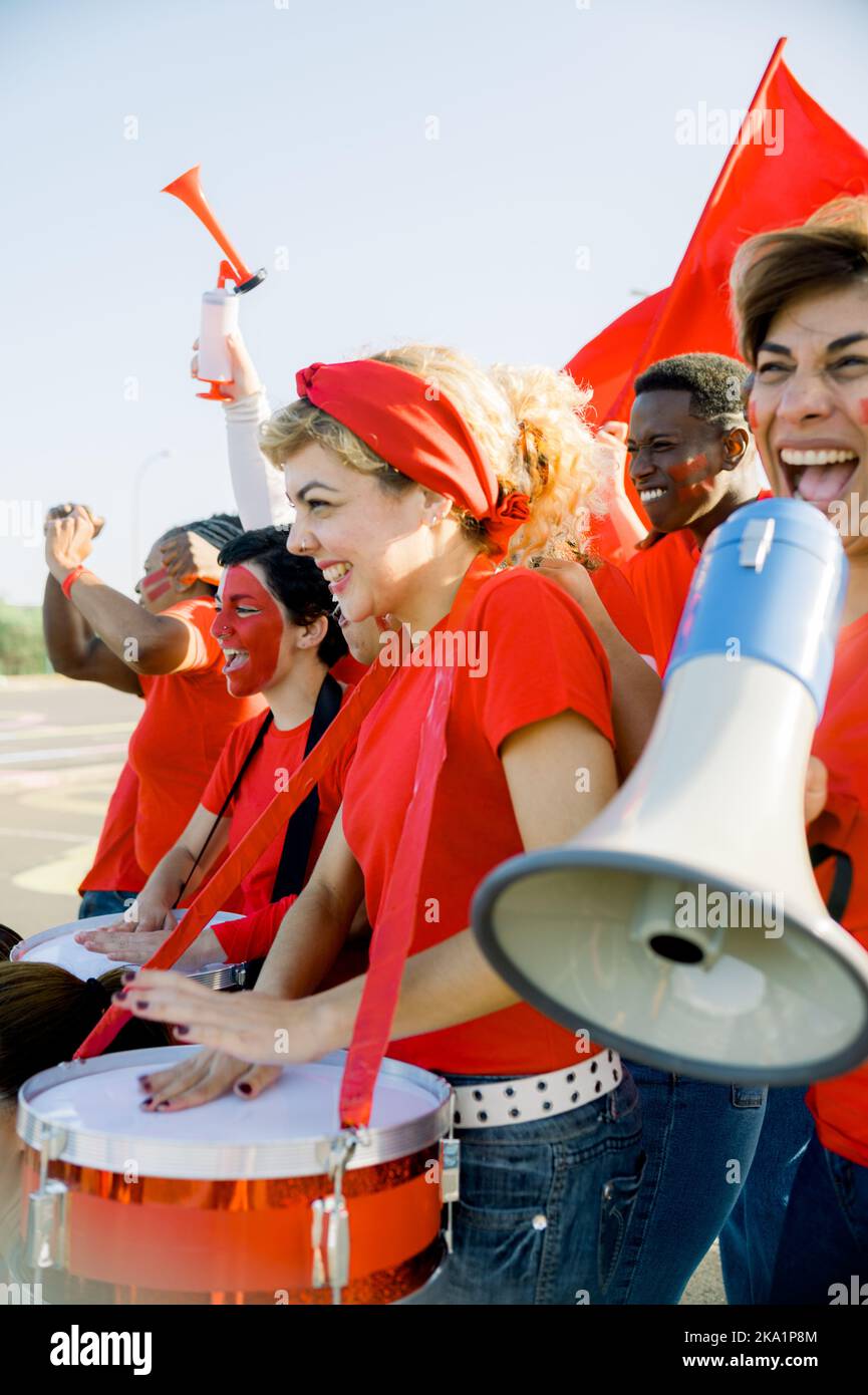 Des fans de football enthousiastes battent des tambours et hurissent en marchant dans la rue Banque D'Images