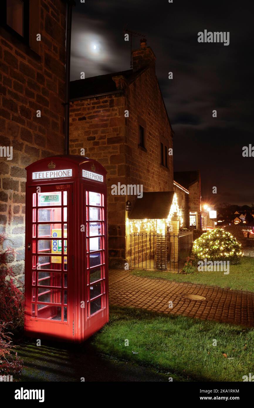 Coffret téléphonique rouge allumé et lumières de Noël à Follifoot, Harrogate, Royaume-Uni Banque D'Images