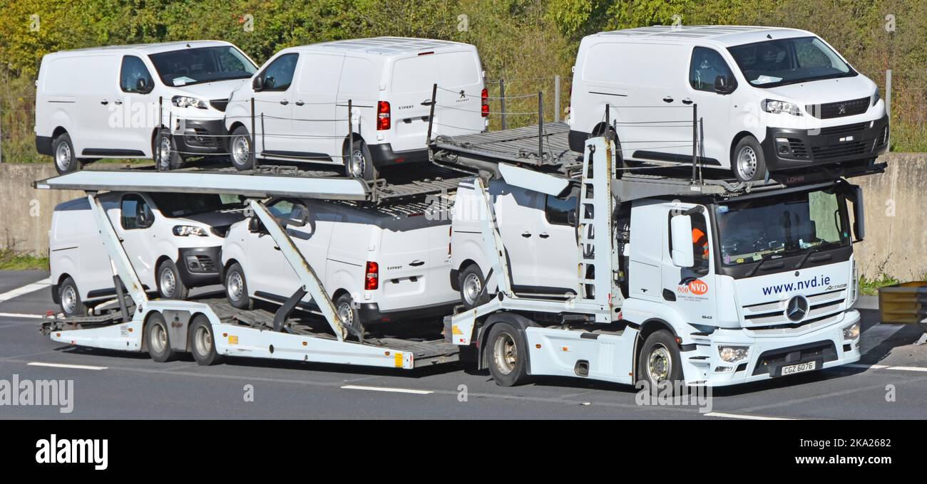 Nouveaux véhicules utilitaires Peugeot Expert blancs chargés et transportés par une remorque de transport articulée et un camion hgv sur la route autoroutière britannique Banque D'Images