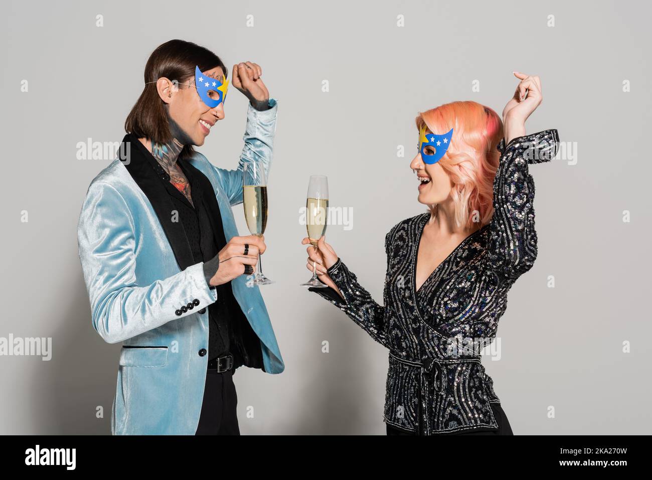 des reines élégantes et heureuses dans des masques de fête dansant avec des  verres à champagne sur fond gris, image de stock Photo Stock - Alamy