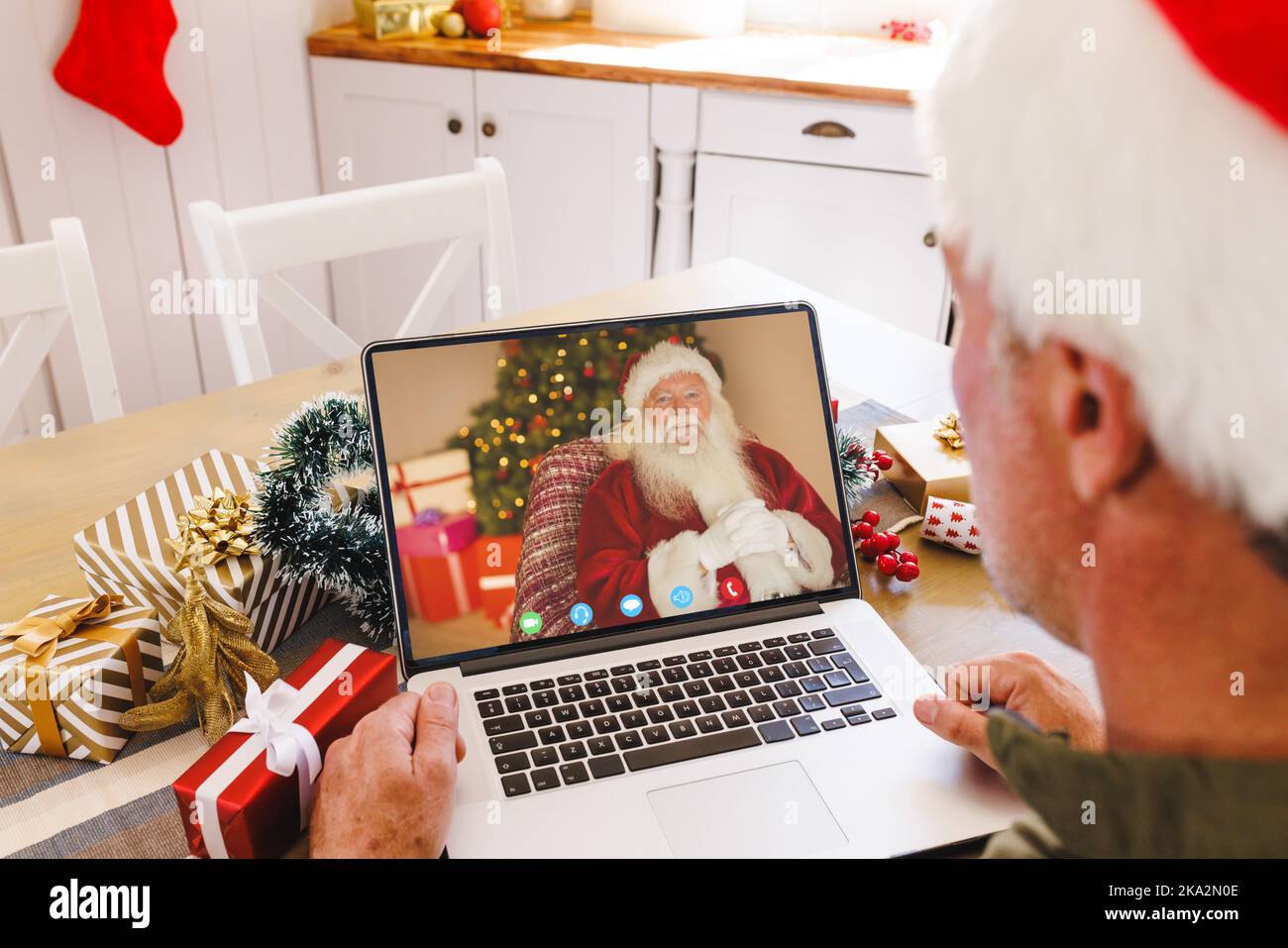 Homme caucasien âgé ayant un appel vidéo de noël avec un homme caucasien portant le costume du père noël Banque D'Images