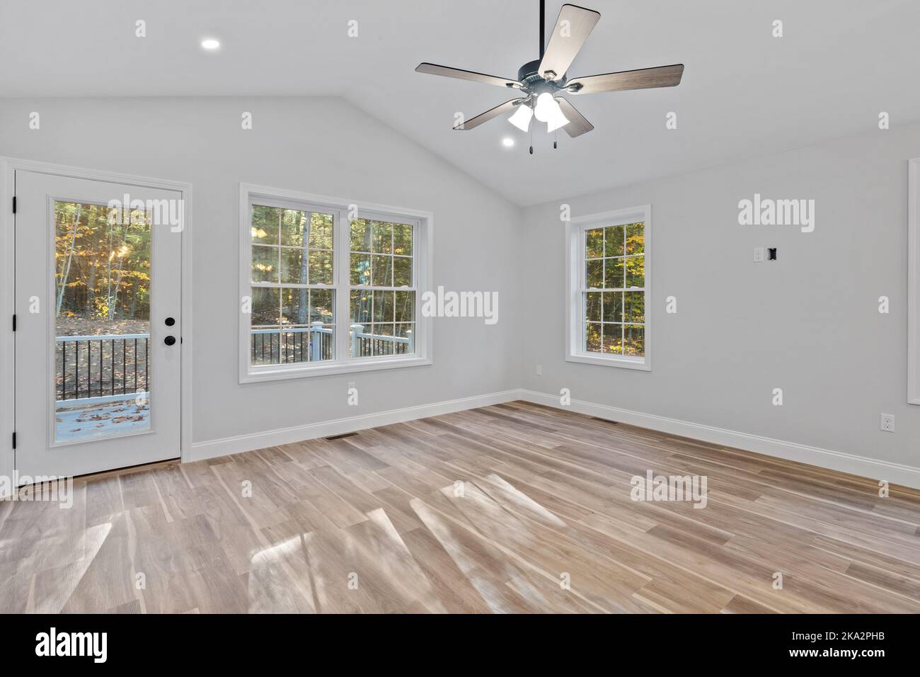 Une vue intérieure sur une maison récemment construite avec des murs blancs, de grandes fenêtres et un ventilateur de plafond Banque D'Images