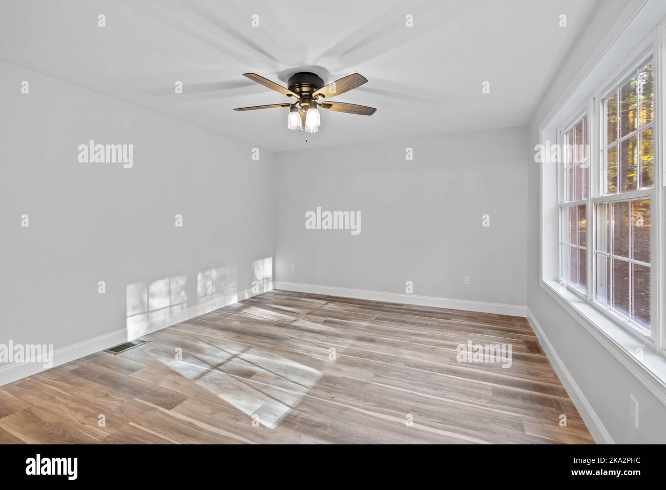 Une pièce blanche vide avec de grandes fenêtres et un ventilateur de plafond dans une maison nouvellement construite Banque D'Images