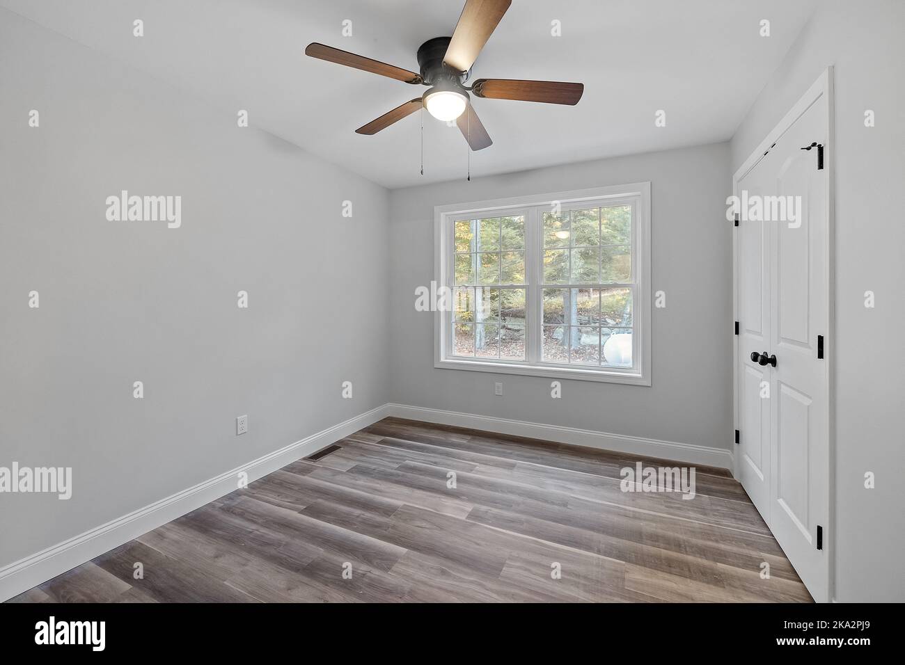Une chambre blanche vide avec des portes en bois et de grandes fenêtres dans une maison nouvellement construite Banque D'Images