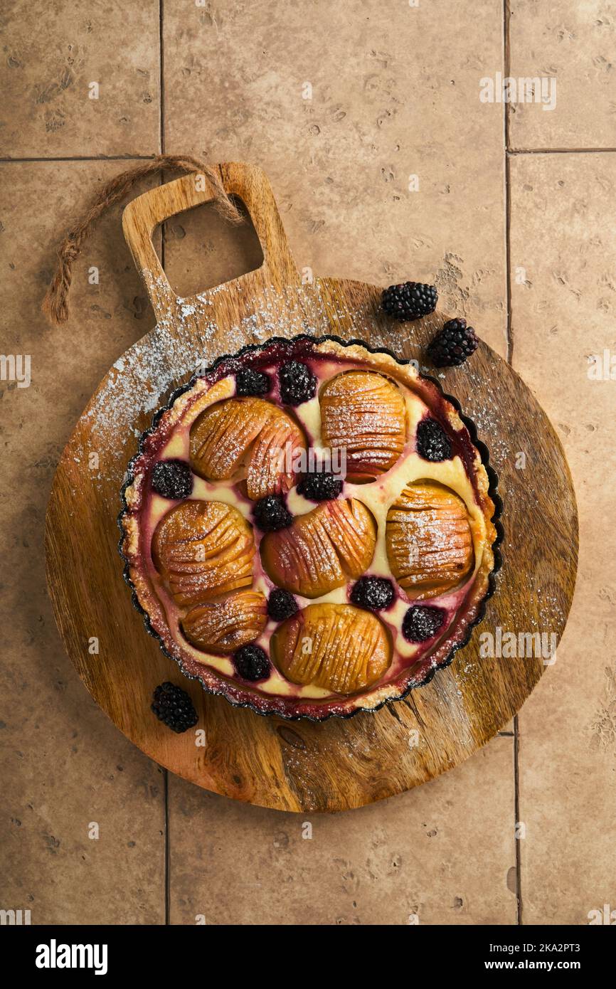 Tarte aux pommes. Gâteau aux pommes et aux mûres ou tarte au sucre en poudre sur une ancienne table en bois. Délicieux dessert pour le dîner d'automne ou d'hiver. Pâtisserie d'automne Banque D'Images