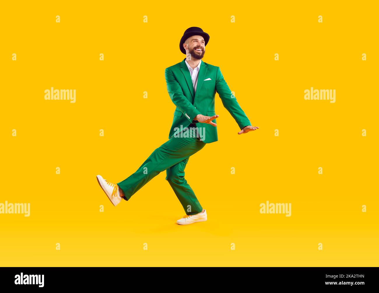 Homme joyeux en costume et chapeau vert moderne danse et s'amuse à célébrer la Saint-Patrick. Banque D'Images
