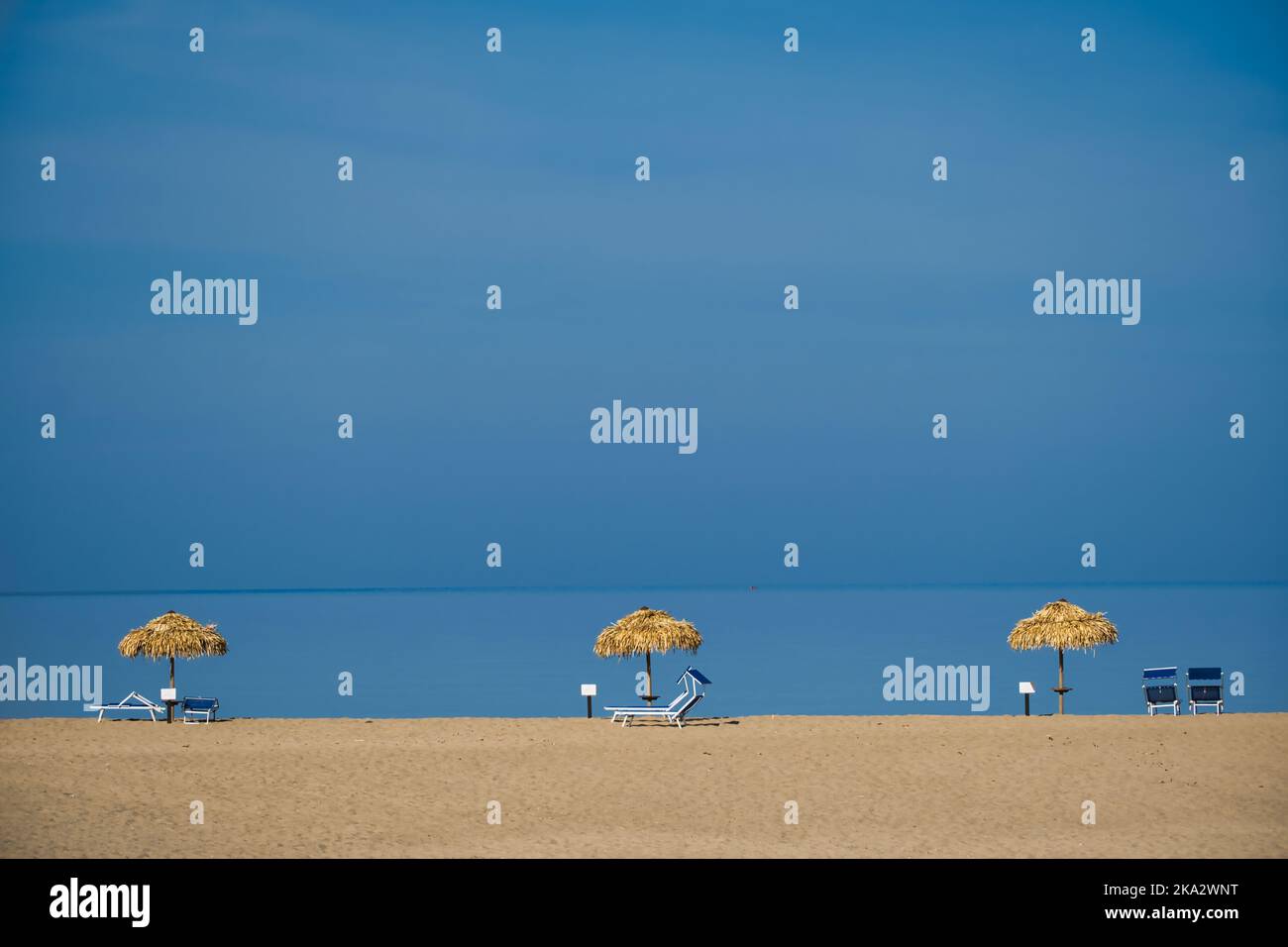 Parasols de plage isolés sans personnes sur la ligne inférieure de l'image avec un grand ciel bleu vide Banque D'Images