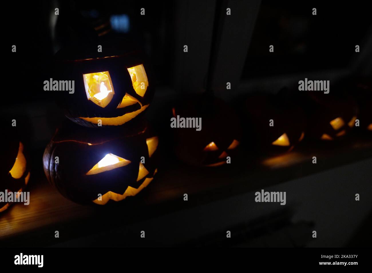 Détails de faible profondeur de champ (mise au point sélective) avec diverses citrouilles d'Halloween sculptées (Jack-o-lanternes) dans l'obscurité avec bougies électriques à l'intérieur. Banque D'Images
